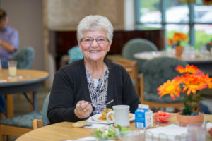 Senior woman enjoying a center meal at an Activity & Dining Centers.